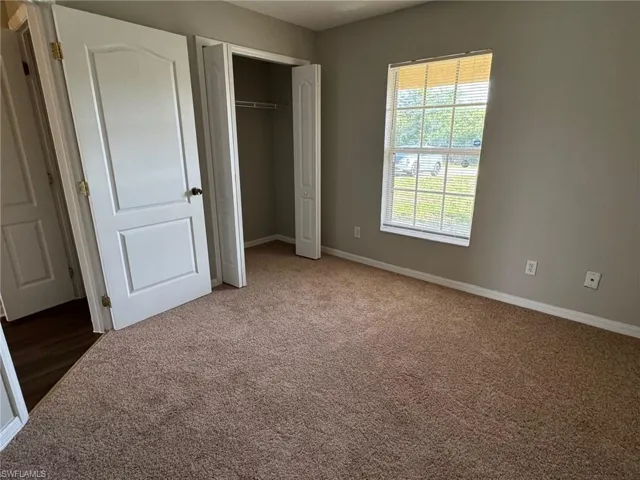 Unfurnished bedroom featuring light colored carpet and a closet
