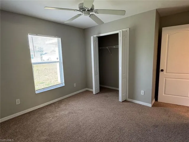 Unfurnished bedroom featuring carpet flooring, a ceiling fan, and a closet