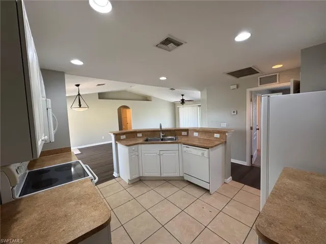 Kitchen with white cabinetry, white appliances, arched walkways, recessed lighting, and light tile patterned flooring