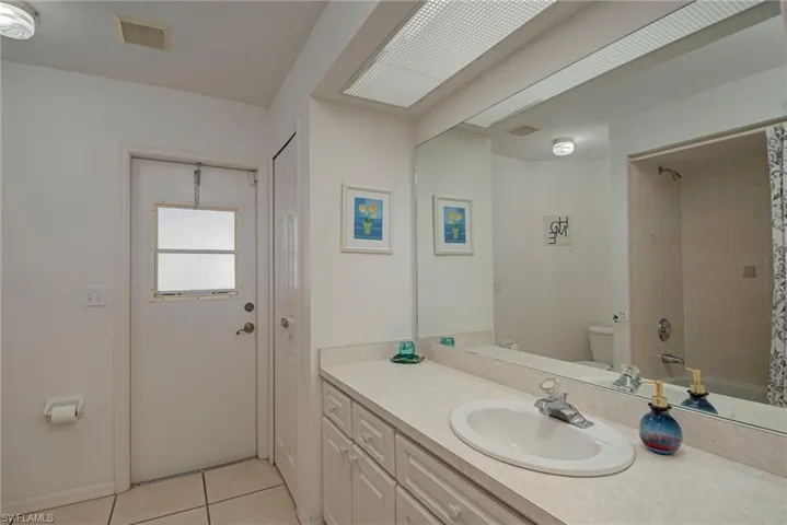 Full bathroom with vanity, light tile patterned floors, and shower / bath combo with shower curtain