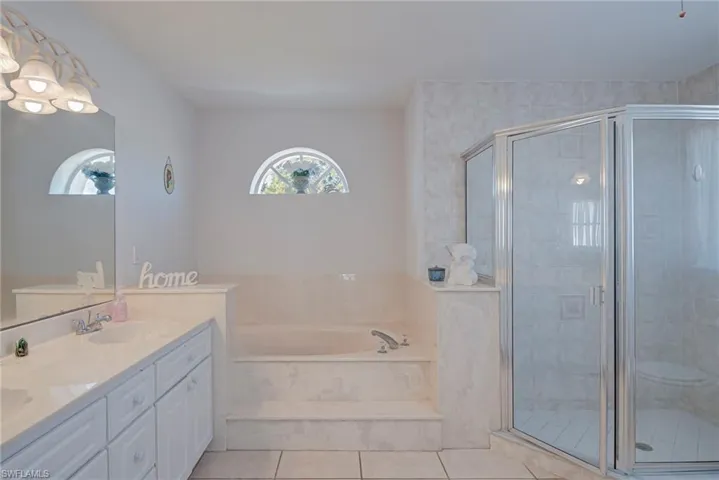 Full bathroom with double vanity, a garden tub, a stall shower, and light tile patterned floors