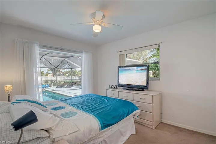 Bedroom with access to exterior, multiple windows, light colored carpet, and ceiling fan