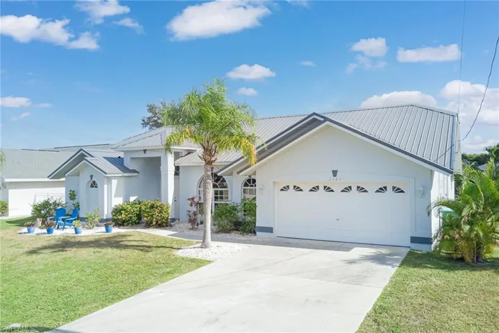View of front facade with a front lawn, a metal roof, an attached garage, and concrete driveway