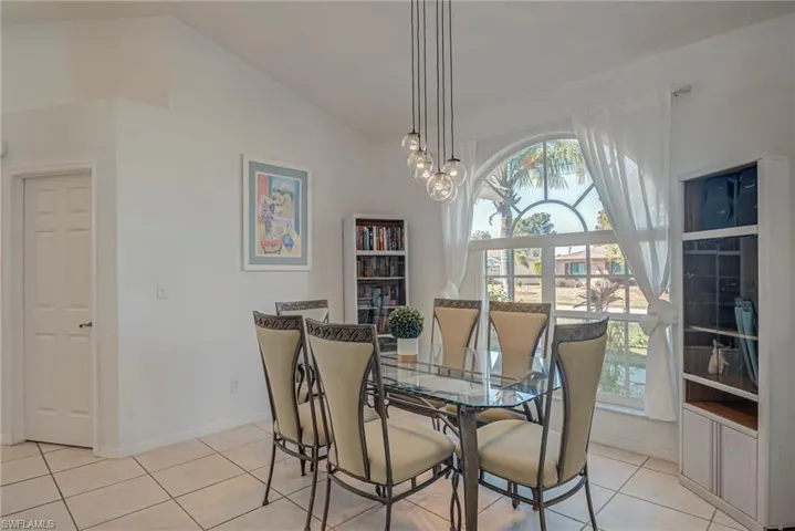 Dining area featuring vaulted ceiling, light tile patterned floors, and a chandelier
