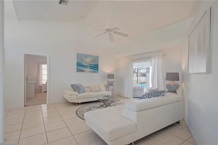 Living area featuring light tile patterned floors, lofted ceiling, plenty of natural light, and a ceiling fan