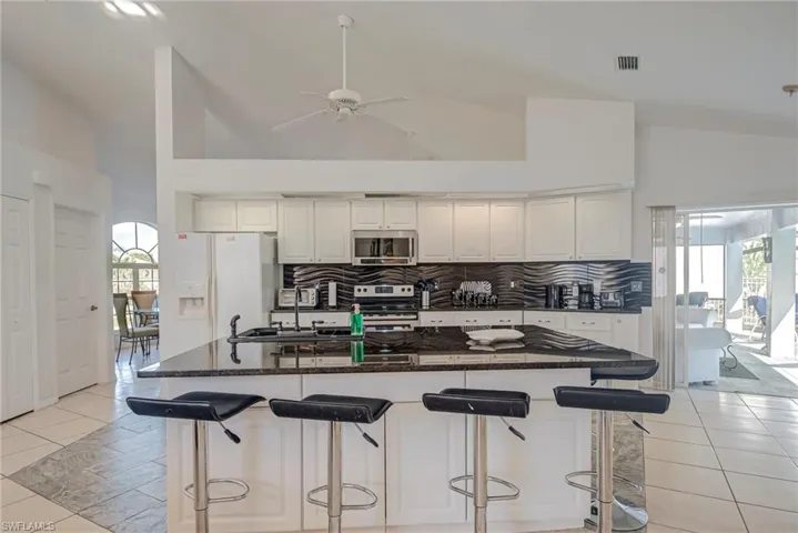 Kitchen with light tile patterned floors, high vaulted ceiling, a kitchen bar, and stainless steel appliances
