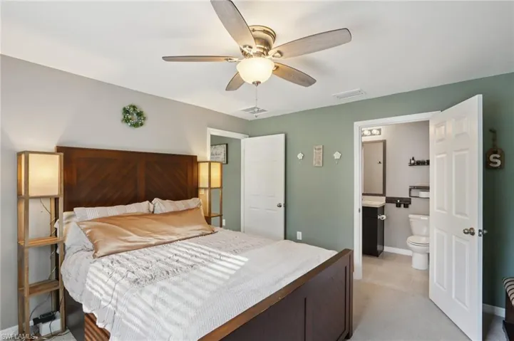 Bedroom featuring light colored carpet, ensuite bathroom, and ceiling fan