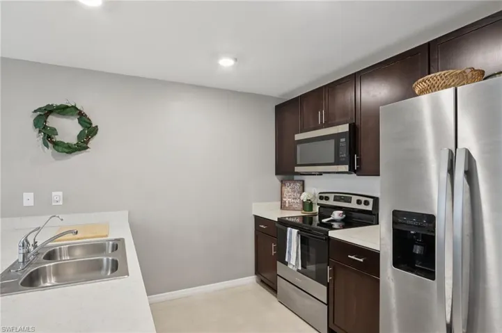 Kitchen featuring appliances with stainless steel finishes, dark brown cabinetry, and light countertops