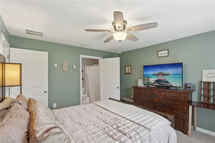 Bedroom with light colored carpet and a ceiling fan