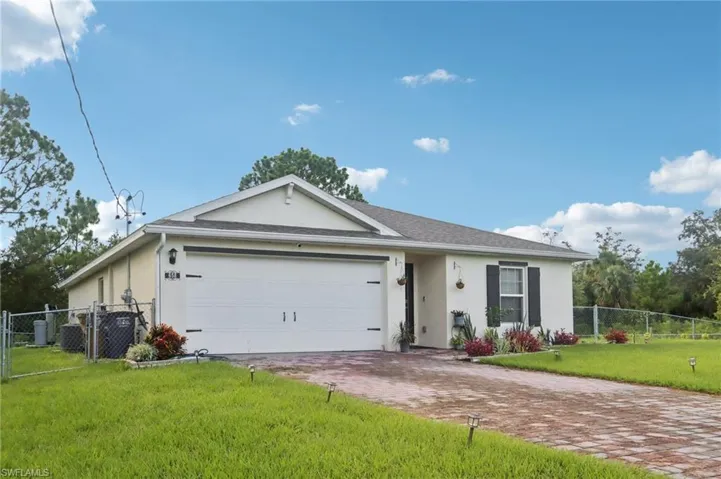 Single story home featuring stucco siding, driveway, a garage, and a gate
