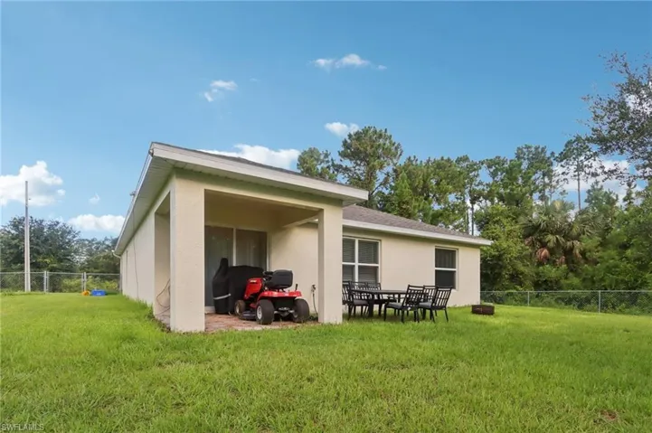 Rear view of house with stucco siding, a patio area, and view of wooded area