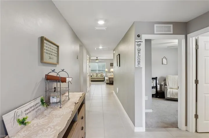 Hall with light tile patterned flooring and light carpet