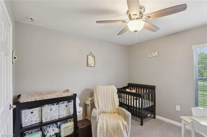 Carpeted bedroom featuring a ceiling fan and baseboards