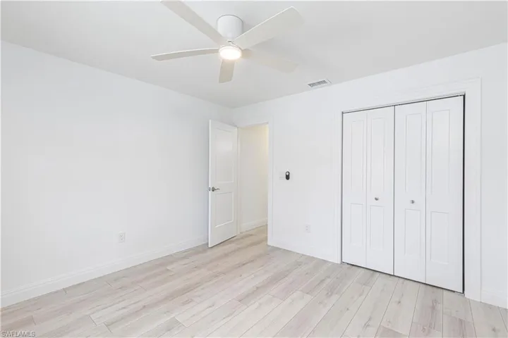 Unfurnished bedroom with ceiling fan, a closet, and light wood-type flooring