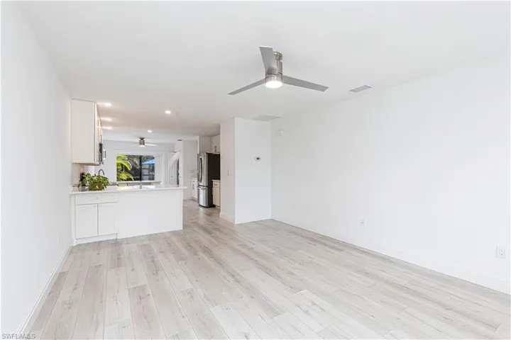 Unfurnished living room with light wood-type flooring and ceiling fan