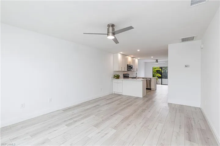 Unfurnished living room with ceiling fan, light hardwood / wood-style floors, and sink