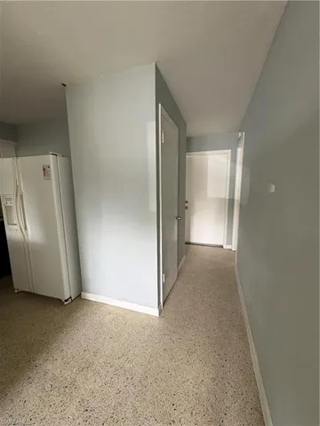 Hallway with baseboards and dark speckled floor