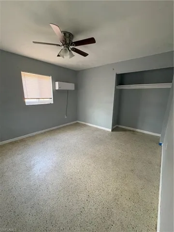 Unfurnished bedroom with dark speckled floor, ceiling fan, and a closet