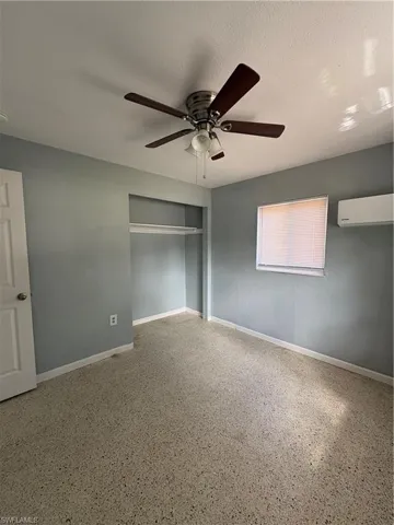 Unfurnished bedroom with a closet, ceiling fan, dark aggregate flooring, and a textured ceiling