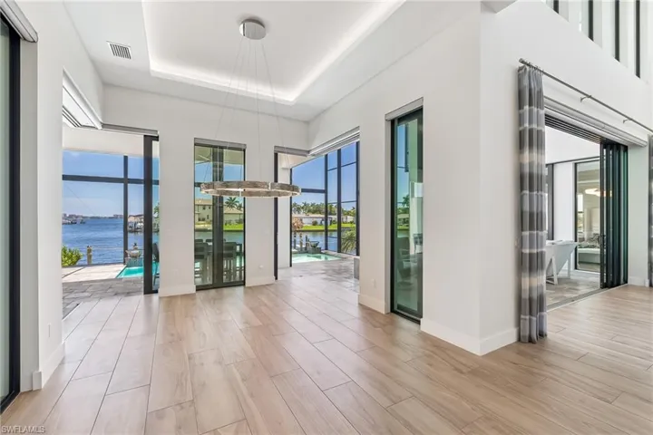 Empty room with a water view, a tray ceiling, and wood finished floors