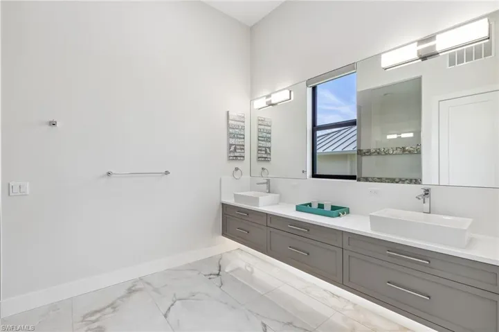 Bathroom with marble look tile flooring and double vanity