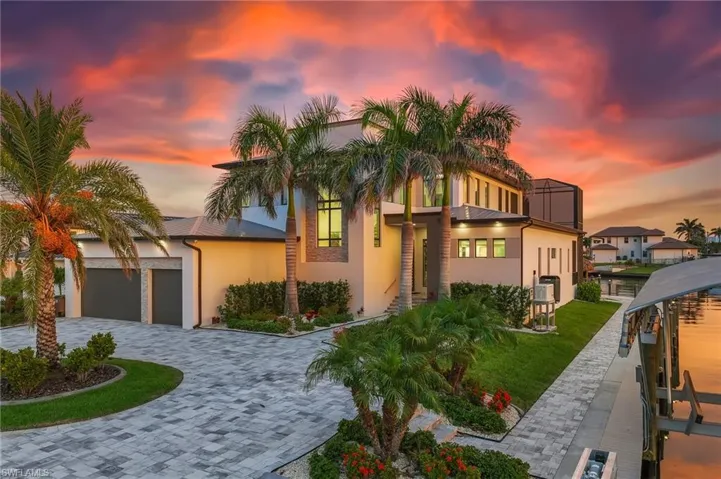 Modern home featuring decorative driveway, stucco siding, a lawn, and a garage