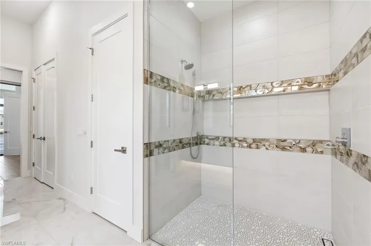 Bathroom with walk in shower and marble finish flooring