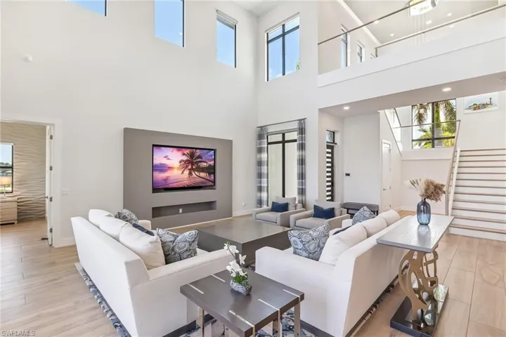 Living area featuring a towering ceiling, stairway, and light wood finished floors