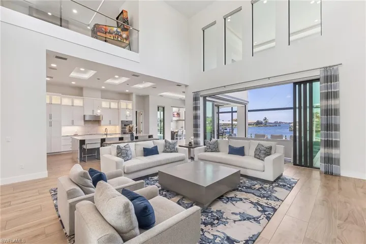 Living area with light wood-type flooring, a water view, a high ceiling, and recessed lighting