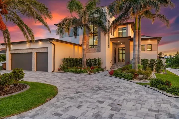 Modern home featuring decorative driveway, stucco siding, and an attached garage