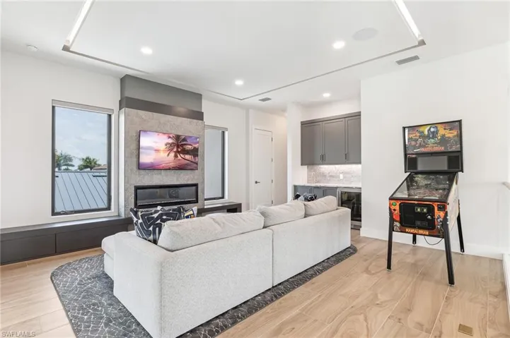 Living area with light wood-style flooring, wine cooler, recessed lighting, and bar area