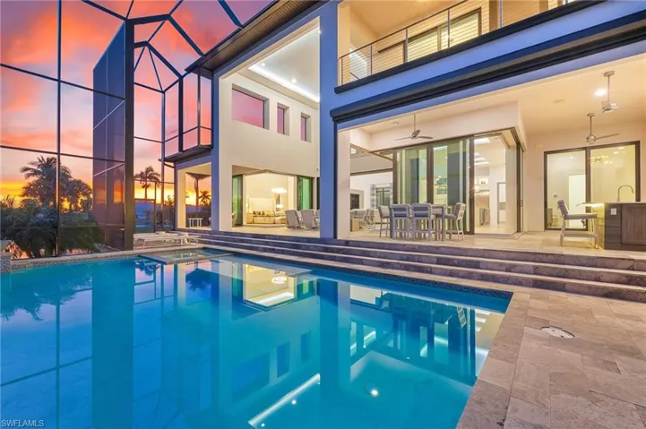 Pool at dusk featuring a ceiling fan, a patio, a lanai, and outdoor dining space