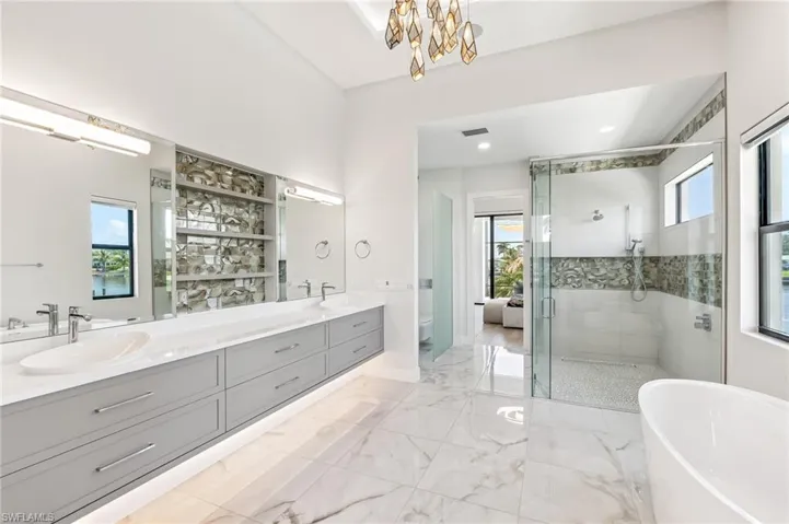 Bathroom featuring plenty of natural light, double vanity, a shower stall, a freestanding bath, and recessed lighting
