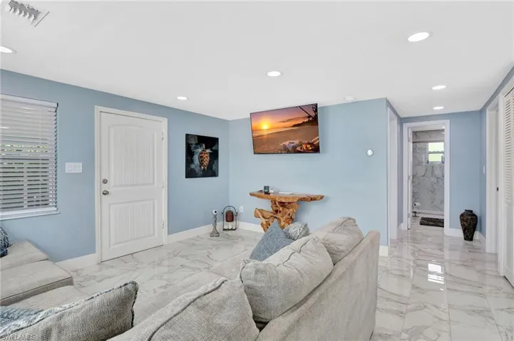 Living room with light marble finish floors and recessed lighting