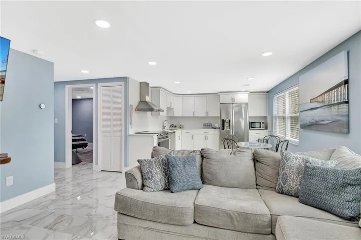 Living area with recessed lighting and light marble finish floors