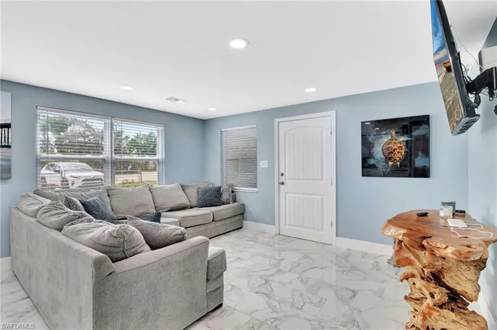 Living area with recessed lighting and light marble finish flooring