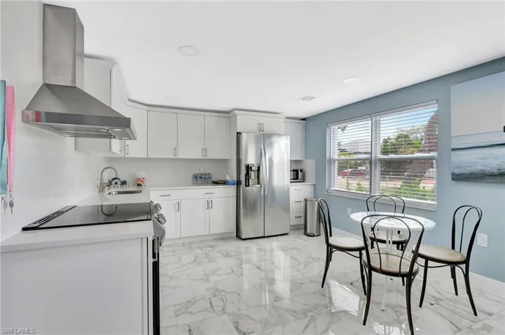 Kitchen featuring stainless steel appliances, light marble finish flooring, white cabinets, and light stone counters
