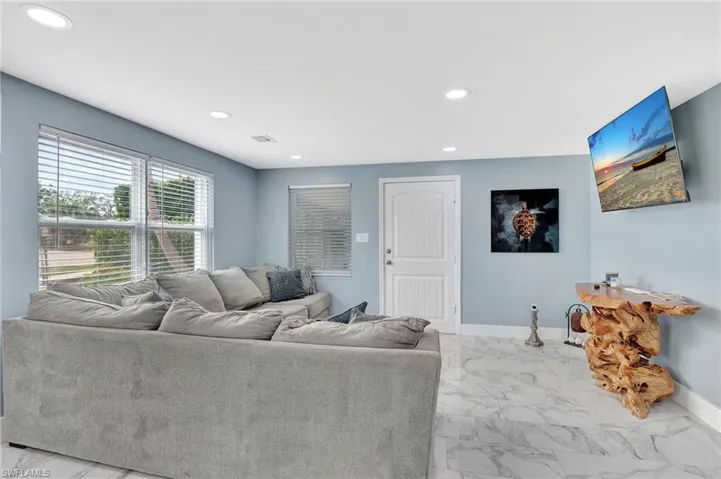 Living area featuring light marble finish floors and recessed lighting