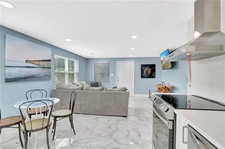 Living area with light marble finish floors and recessed lighting