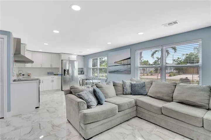 Living area with recessed lighting and light marble finish floors