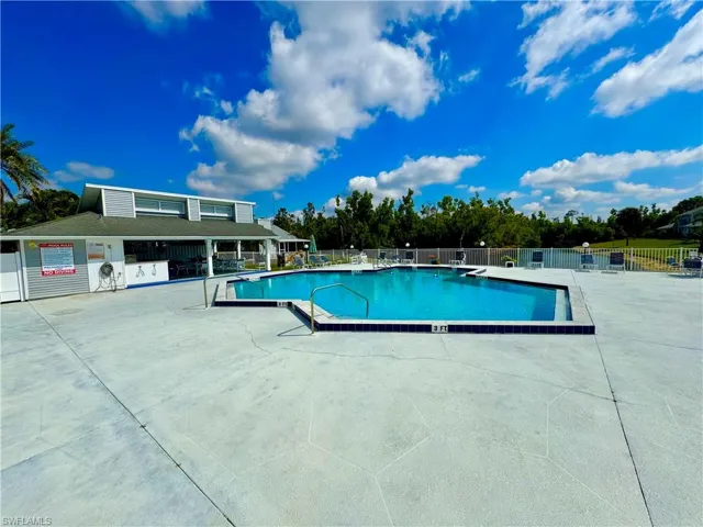 Community pool featuring a patio area and fence