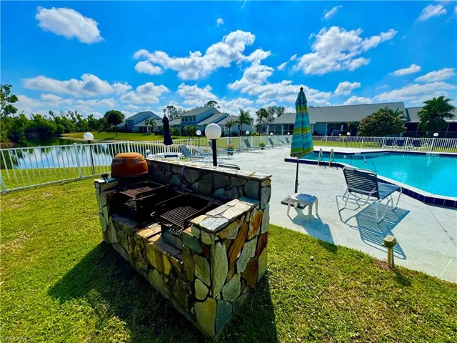 Pool with a yard, a patio area, fence, and a water view