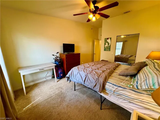 Carpeted bedroom with a ceiling fan and visible vents