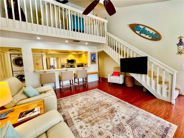 Living area with wood finished floors, stacked washer and clothes dryer, a towering ceiling, and stairs
