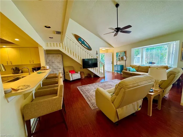 Living area featuring lofted ceiling, stairway, a textured ceiling, and wood finished floors