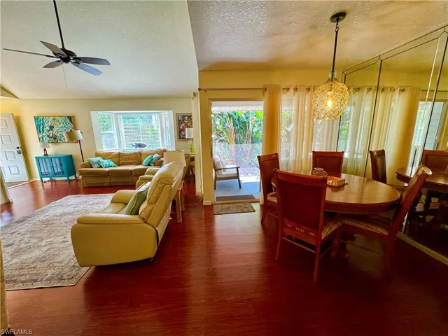 Dining room featuring lofted ceiling, ceiling fan, a textured ceiling, and wood finished floors