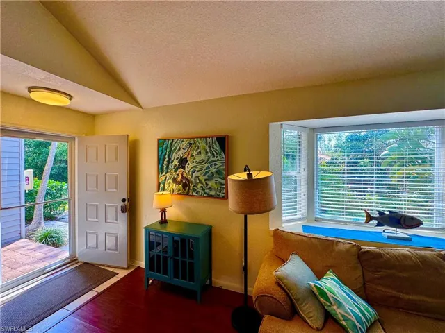 Foyer featuring lofted ceiling, a textured ceiling, and wood finished floors
