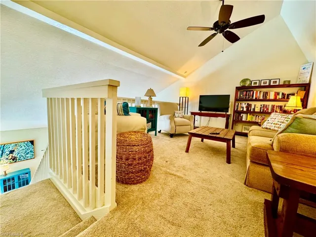 Living area with lofted ceiling, a textured ceiling, and carpet flooring