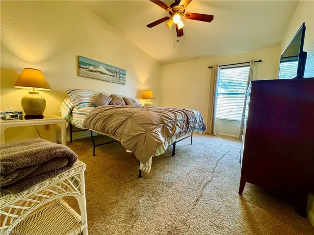 Carpeted bedroom featuring lofted ceiling and ceiling fan