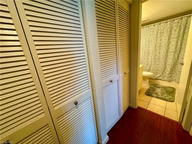 Full bath with curtained shower, a closet, toilet, and tile patterned floors
